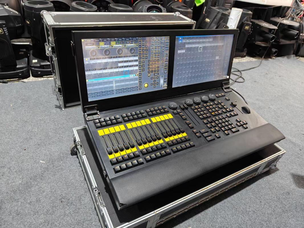 Console DMX professionnelle de type station de travail dans une régie lumière de salle de spectacle, écrans allumés affichant