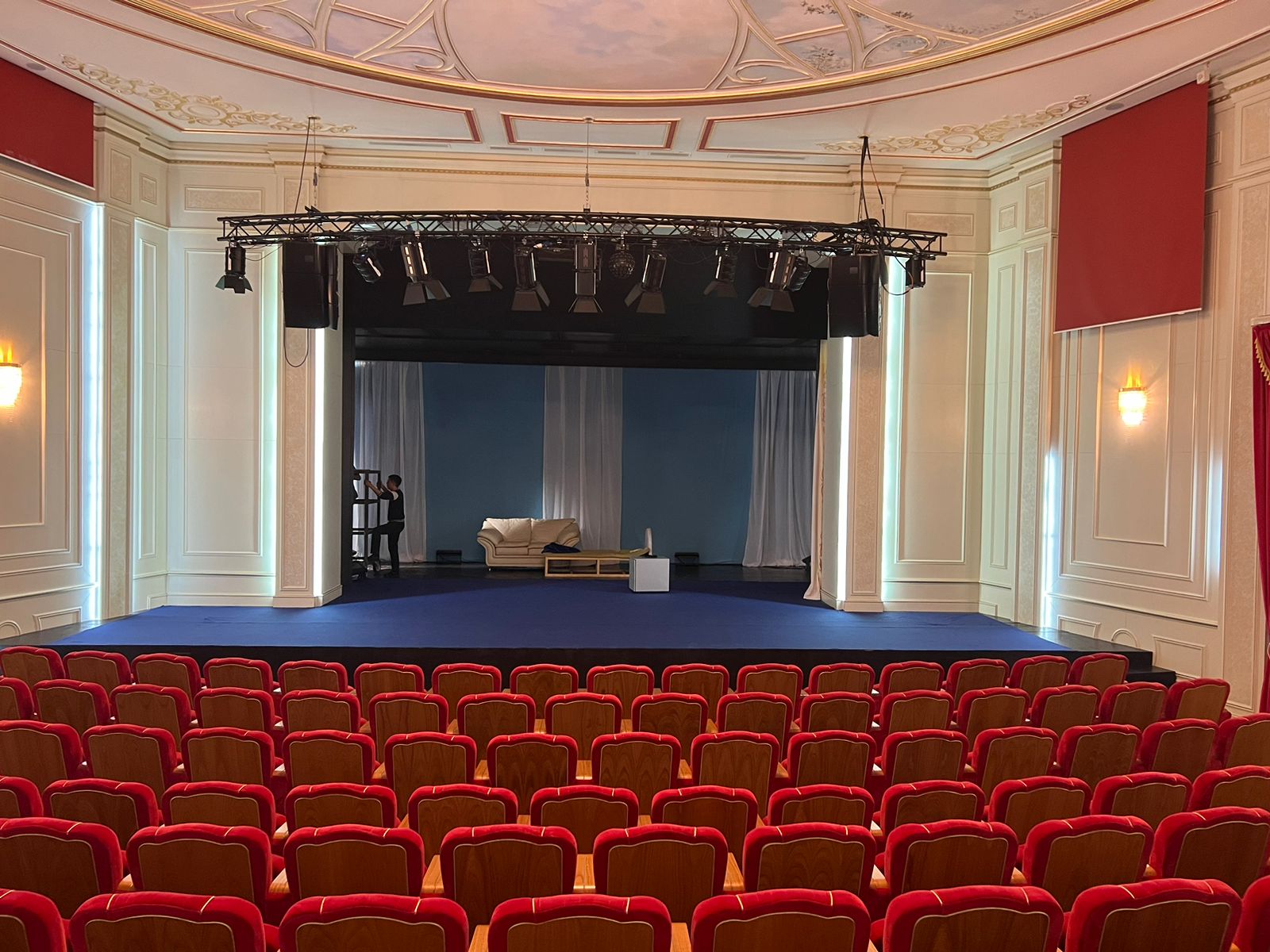 Gros plan sur les faders pondérés et l'écran tactile d'une console DMX dédiée au théâtre, interface de programmation visible.