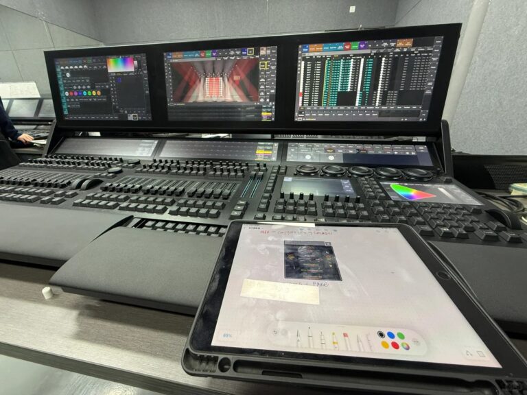 Console DMX MA Lighting grandMA3 full-size en action dans un environnement de travail professionnel, avec ses trois écrans ta